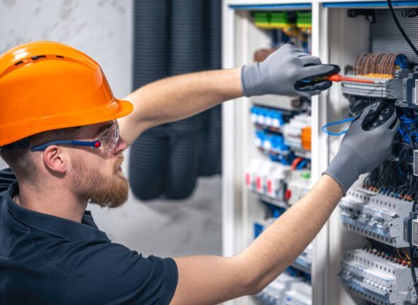 Tradesperson using tools to work on an electrical switchboard