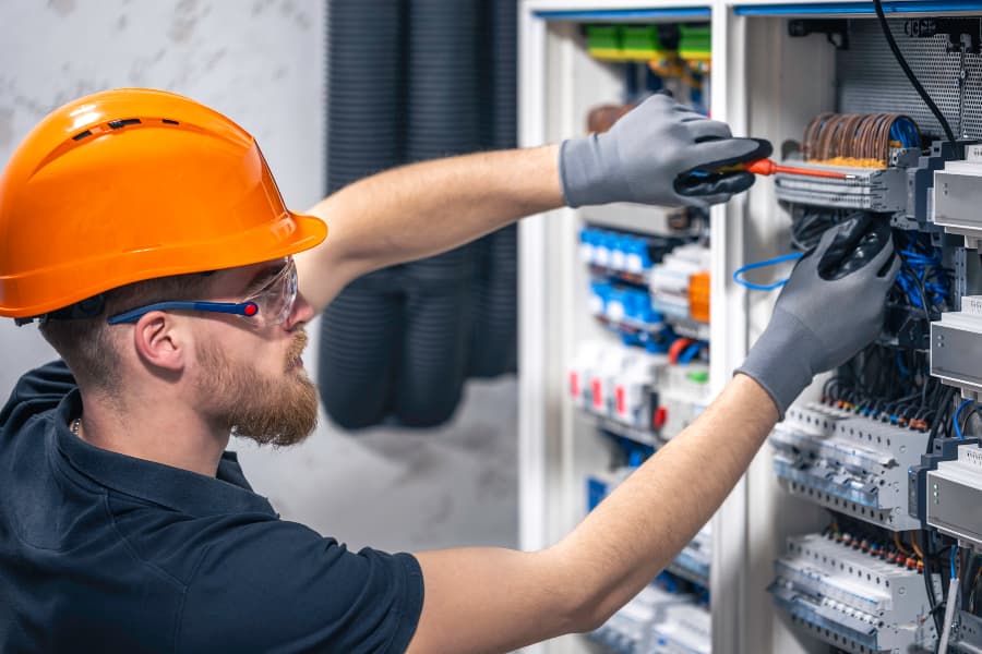 Tradesperson using tools to work on an electrical switchboard