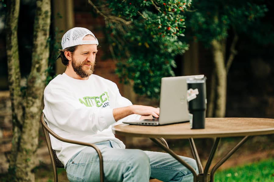 Unitech training academy online student on computer outside